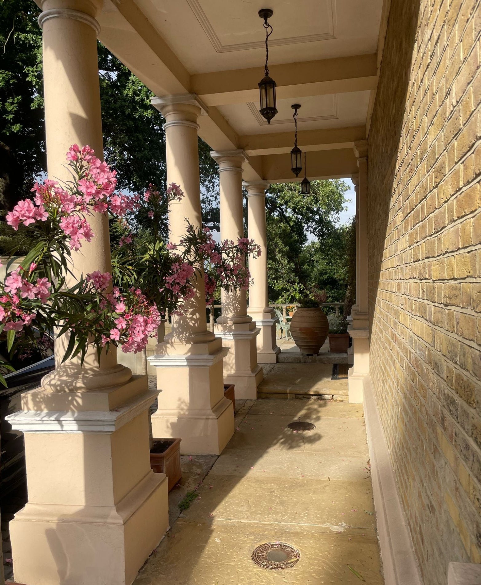 Patio with columns, flowers, and a brick wall